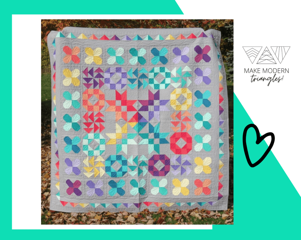 Large modern type quilt with modern triangles and brightly colored quilt on a gray background made by Make Modern Triangle member. 