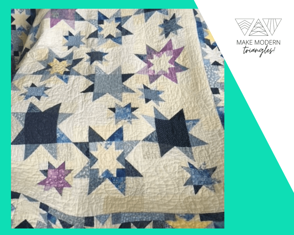 Quilt made with varied sizes of star blocks in blue and violet fabrics.