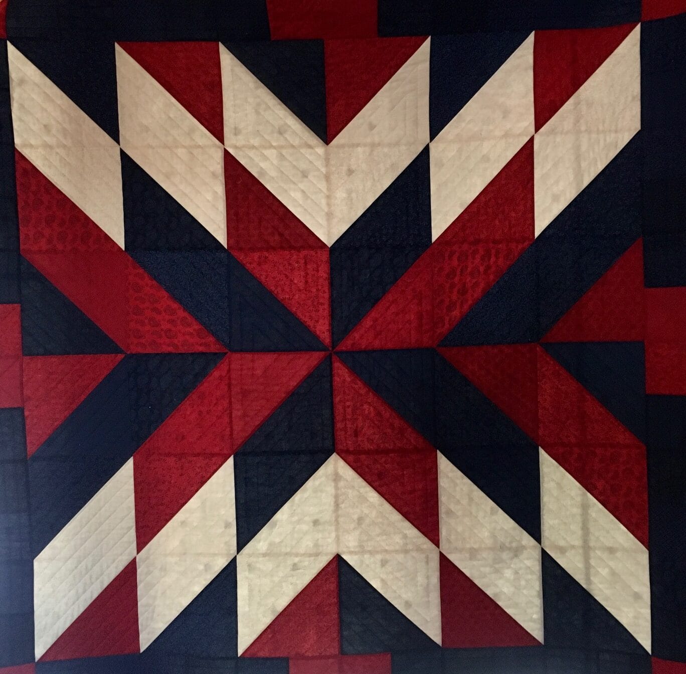 Modern triangle quilt made by Lonnie W. with black, red and ecru fabric colors.