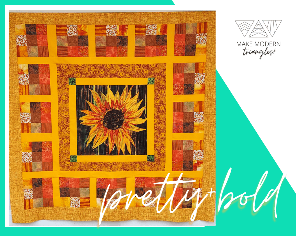 Sunflower motif panel has nine-patch borders in red, gold, yellow and orange prints.