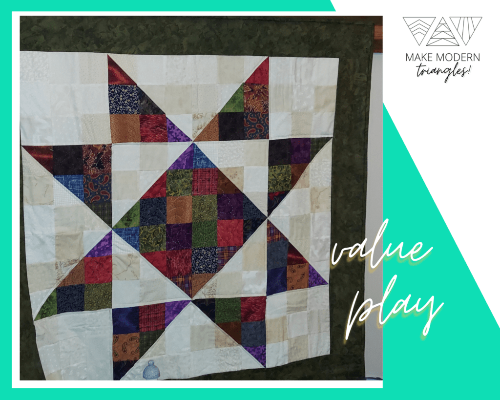 Make Modern Triangles spotlight member Coleen's quilt made with half-square triangles to form a center star.