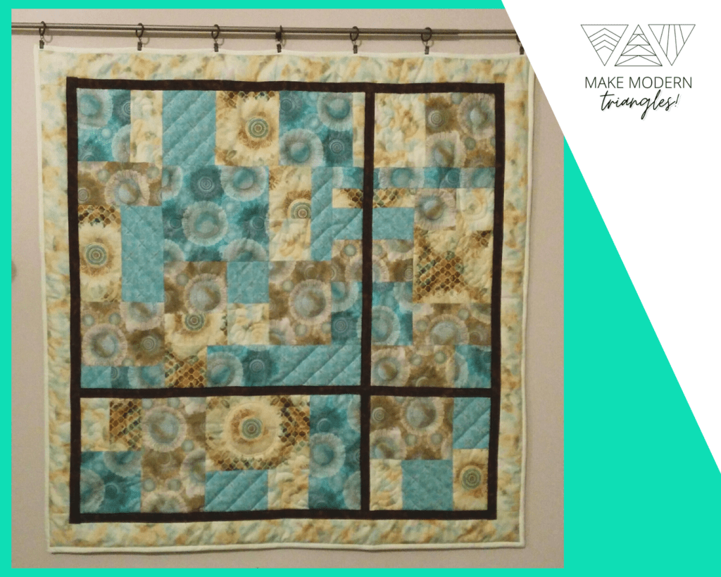 Quilted wall hanging in teal, tan and brown colors.