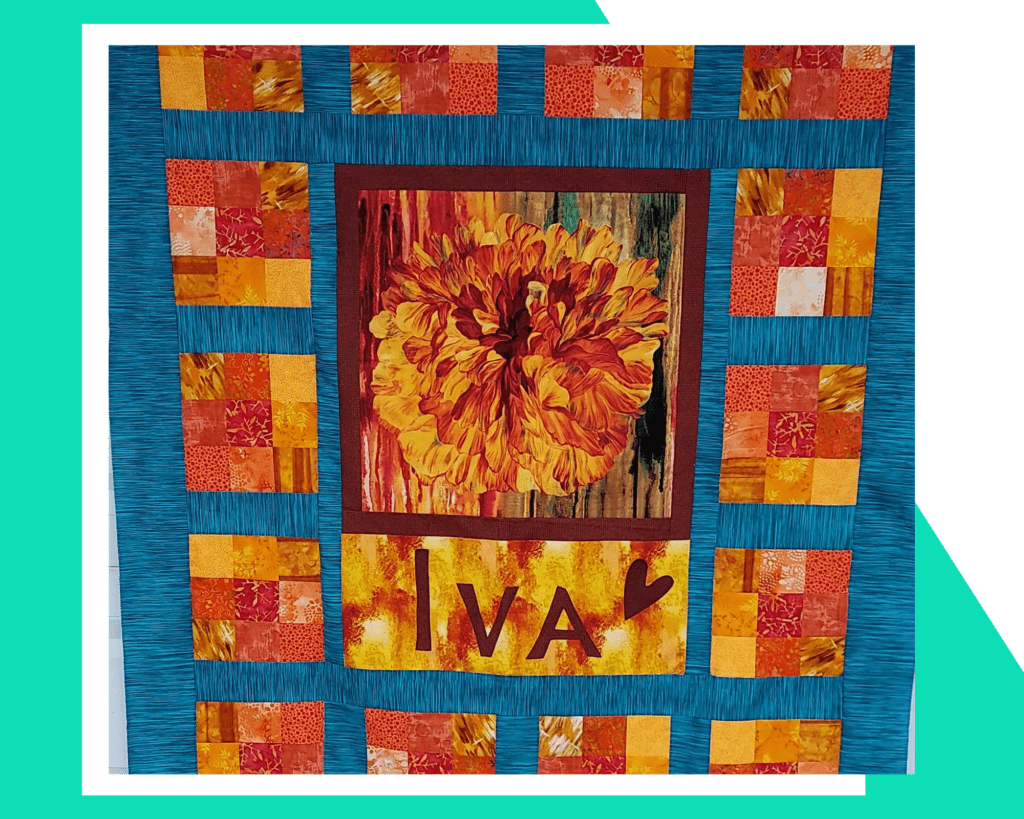 Nine-patch blocks border large flower panel in the center of the quilt. Made in bright yellow, oranges and reds. Made  Coleen S., the  Make Modern Triangles featured member spotlight .