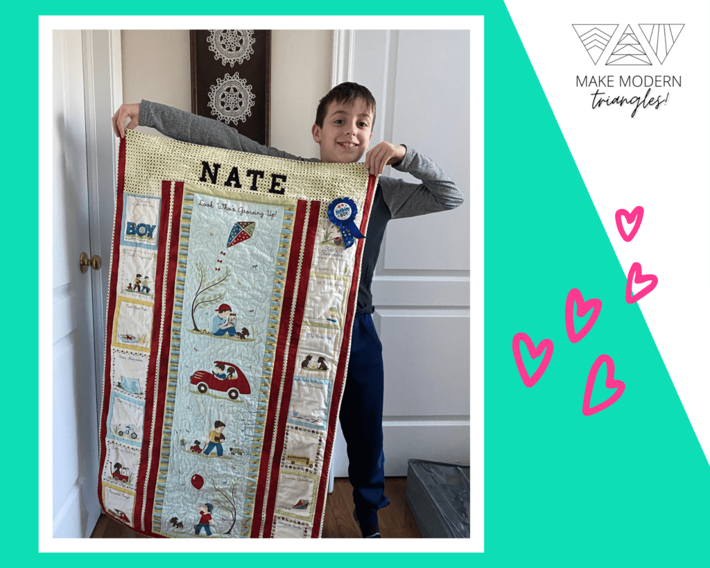 Nate holds up a quilt made for him by Marilyn W., member spotlight for Make Modern Triangles,