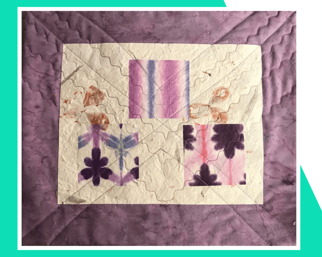 Art quilt made with pink and purple fabrics depicting flowers.