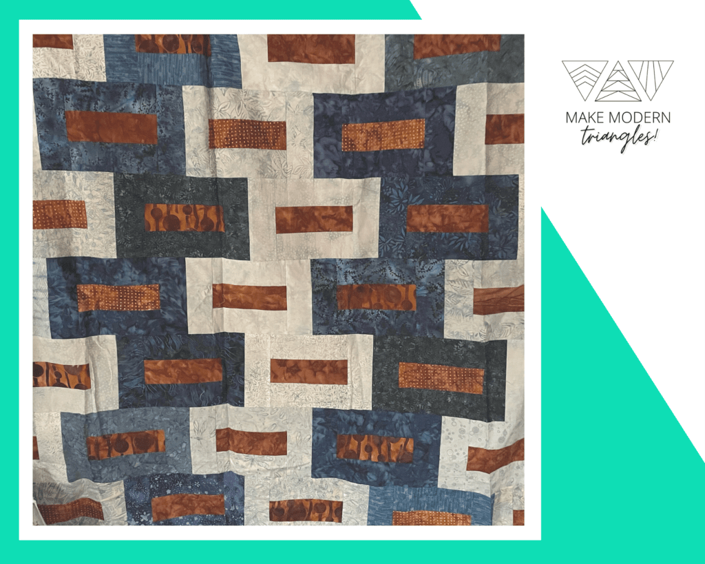 Dark blue, brown and ecru colored blocks form a modern quilt block pattern. Made by Marilyn W., the member spotlight for Make Modern Triangles,