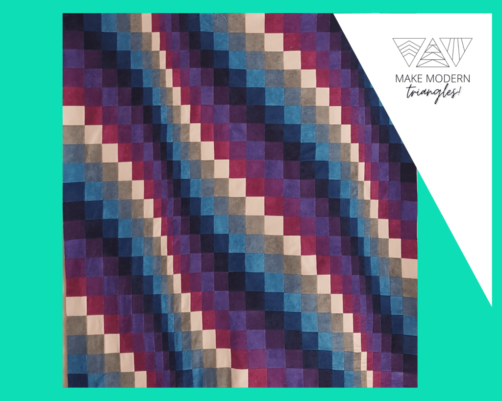 Image of a bargello quilt pattern in purple, magenta, peach and various blue fabrics made by Stephanie A.