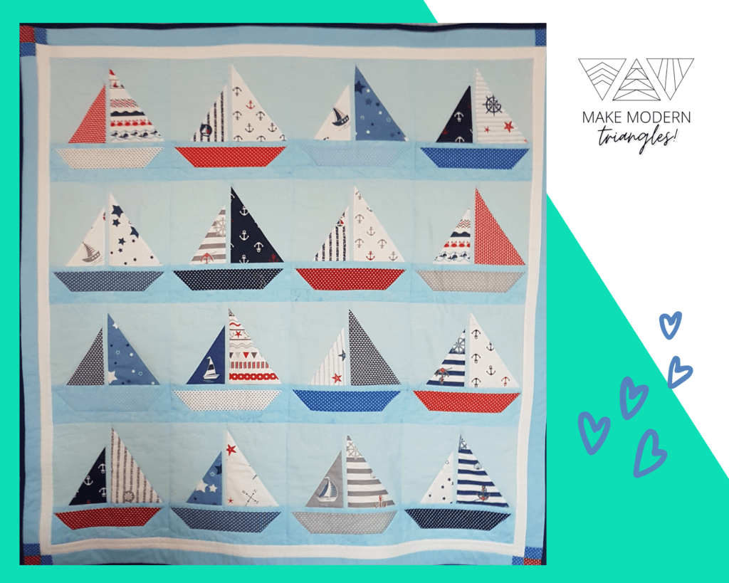 Image of a sailboat motif quilt in blue, orange, red and navy fabrics.