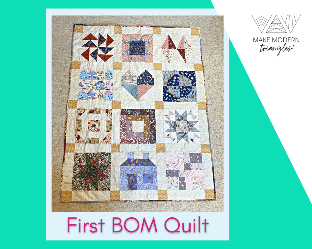 Make Modern Triangles member spotlight Cathy H. first BOM quilt - a sampler block quilt in blues, pinks, red , gold and navy.