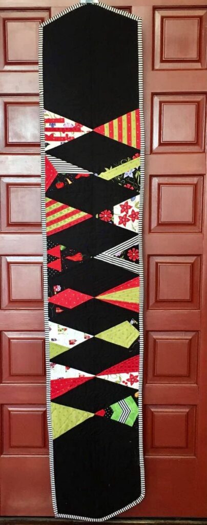 Member Lonnie W. made a table runner with her triangle trees and included the Day 3 striped blocks in red and yellow fabrics.