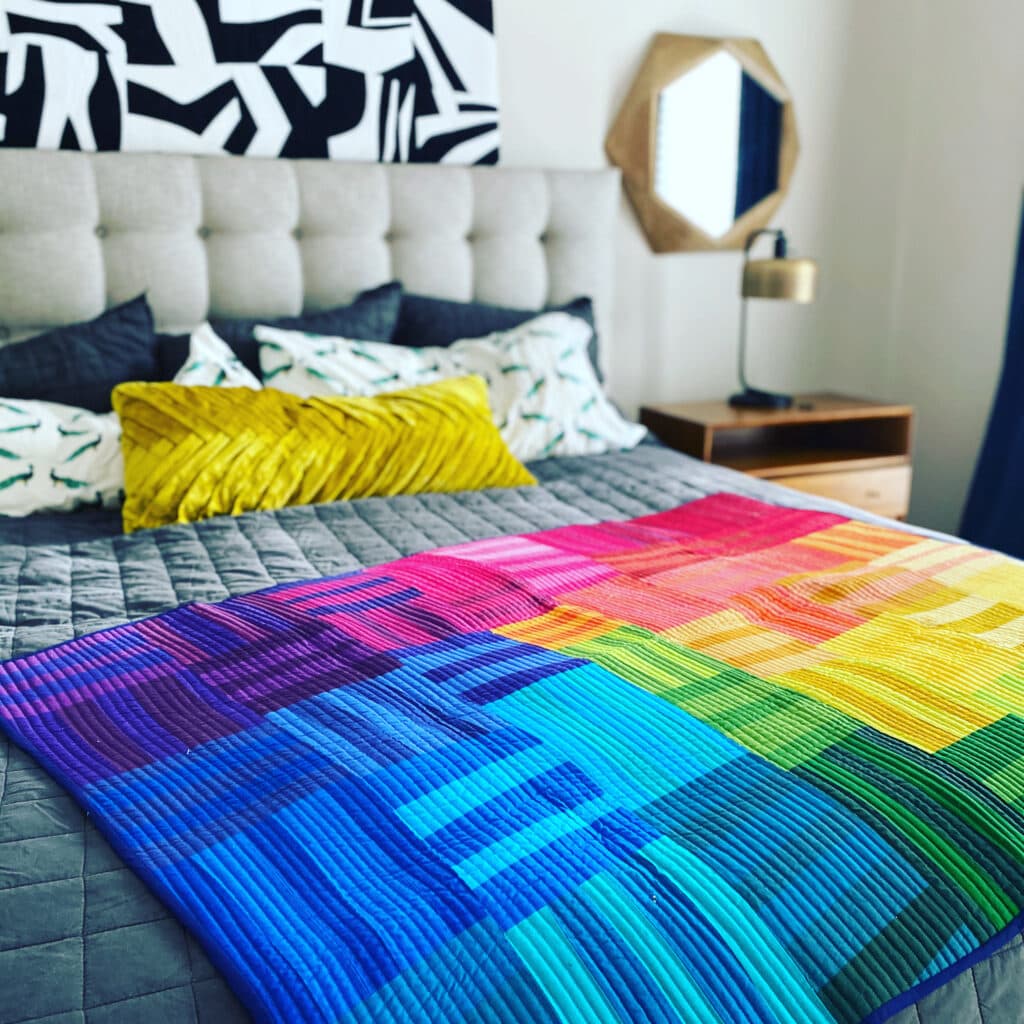 Photo shows Rainbow Remix and Black and White quilt, both are improv quilts by Bryan House Quilts