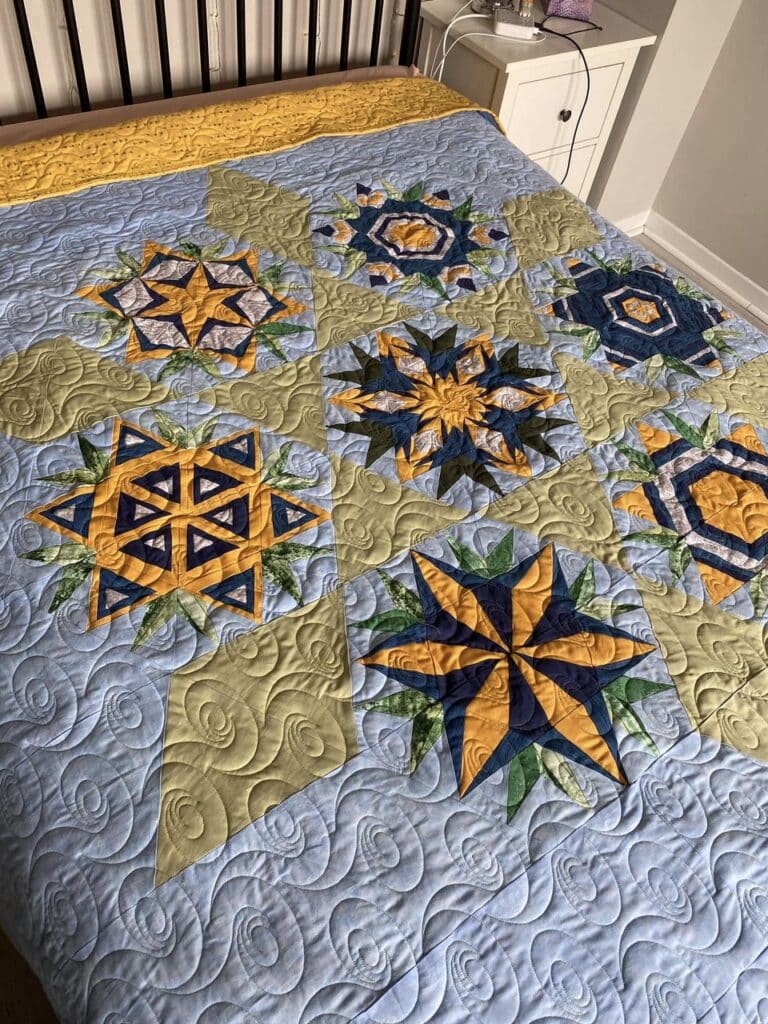 Ann G.. displays her Wildflower BOM quilt finish from the make modern triangles BOM program.