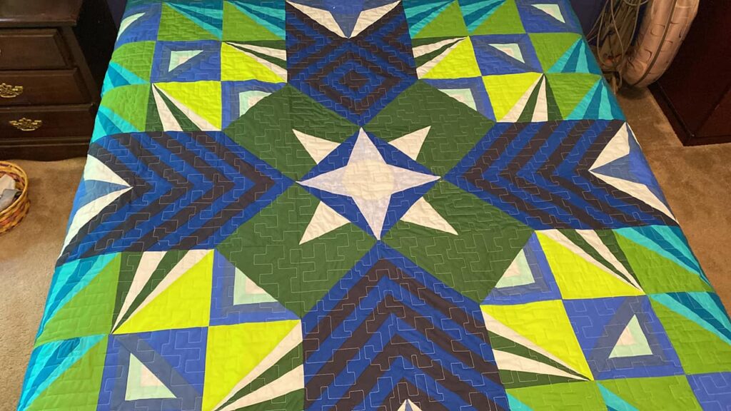 Judith B. displays her Sparkler BOM quilt finish from the make modern triangles BOM program.