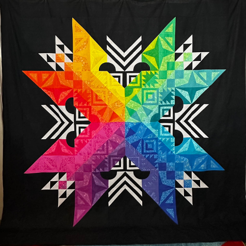 Quilt finishes by Make Modern Triangles members - Aurora BOM by Jennifer L. in rainbow color palette.