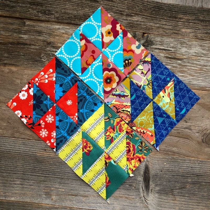 Four completed HST blocks with brightly colored fabric scraps from hello houston quilt tutorial